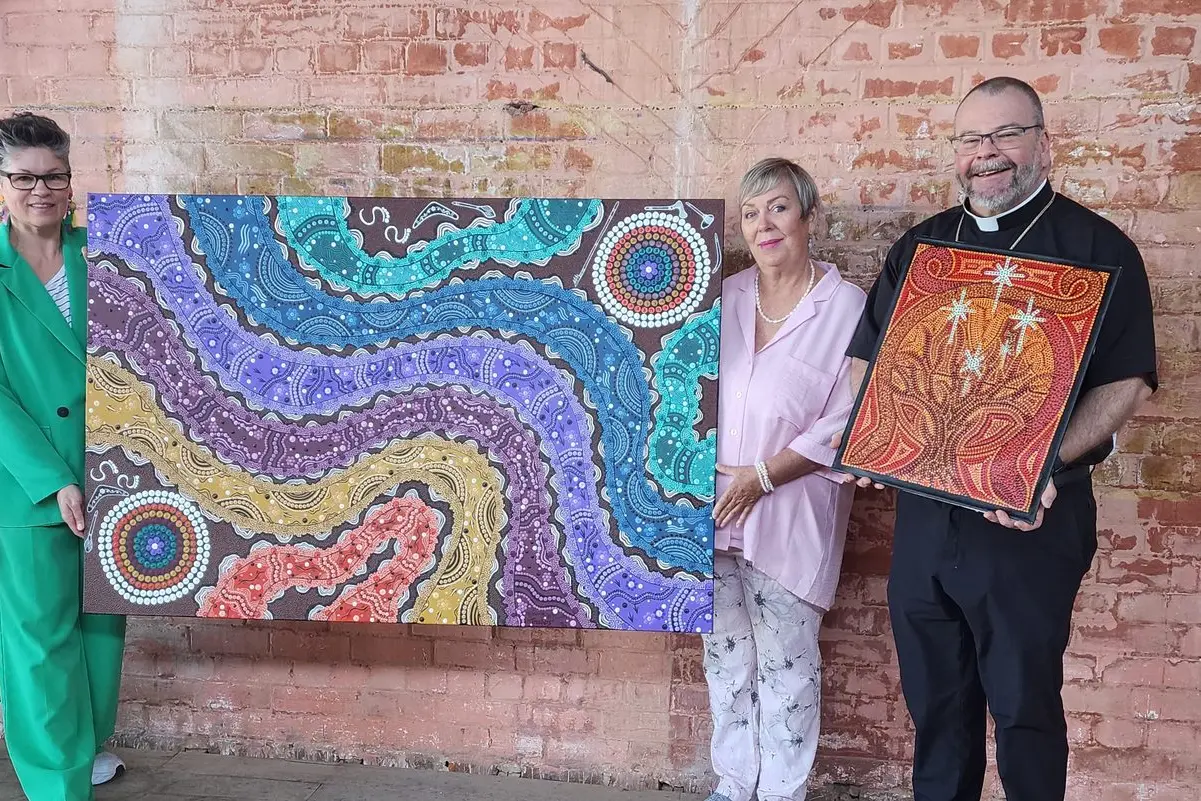 The 2025 CatholicCare Wilcannia-Forbes Aboriginal Art Competition is open for entries again. Pictured are the winning artworks in 2023 with judges Bishop Columba Macbeth-Green of the Catholic Diocese of Wilcannia-Forbes (right), CatholicCare Wilcannia-Forbes CEO Anne-Marie Mioche (centre) and Red Bend Catholic College visual arts teacher Tracie Axton (left). PHOTO: Supplied