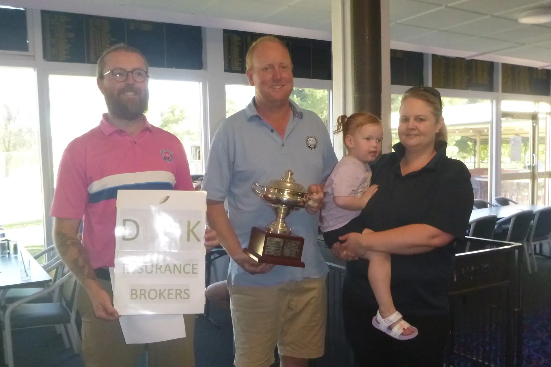 <p>Head Pro Will presents a trophy to the Mixed Foursomes Scratch and Handicap winners \\u2013 John Betland and Nicole Death holding Charley.</p>\\n