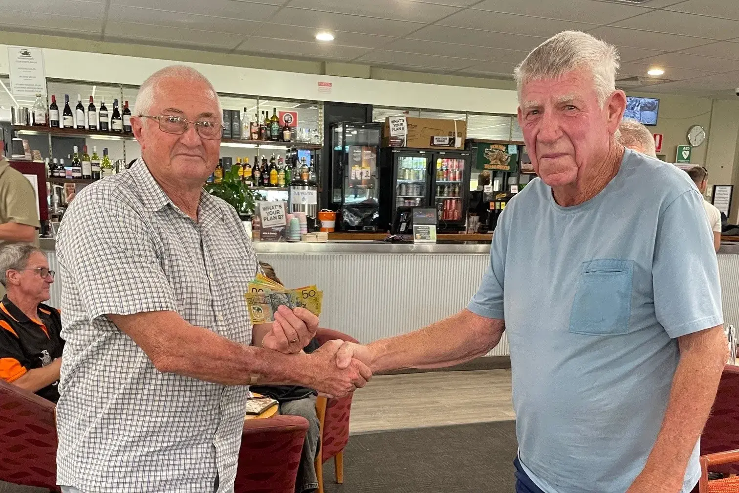 <p>John Shrader from CanAssist accepts the bowls day proceeds from John Cutler. </p>\\n