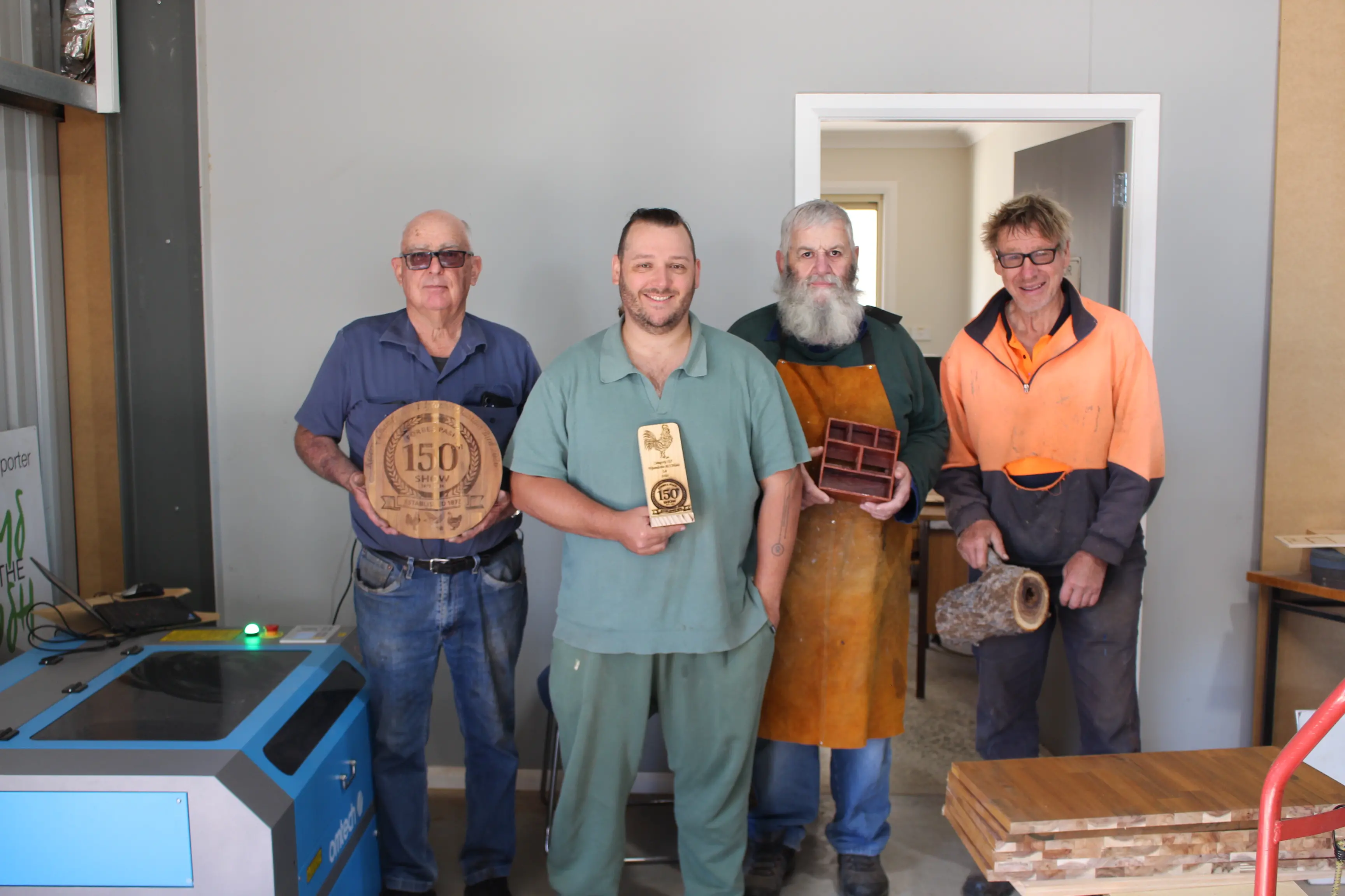<p>Peter Norris, Ryan Barlow, Bill Little and John Perry with some of their recent work, including laser engraved wood plaques for the Forbes Show. PHOTO: Brendan McCool</p>\\n